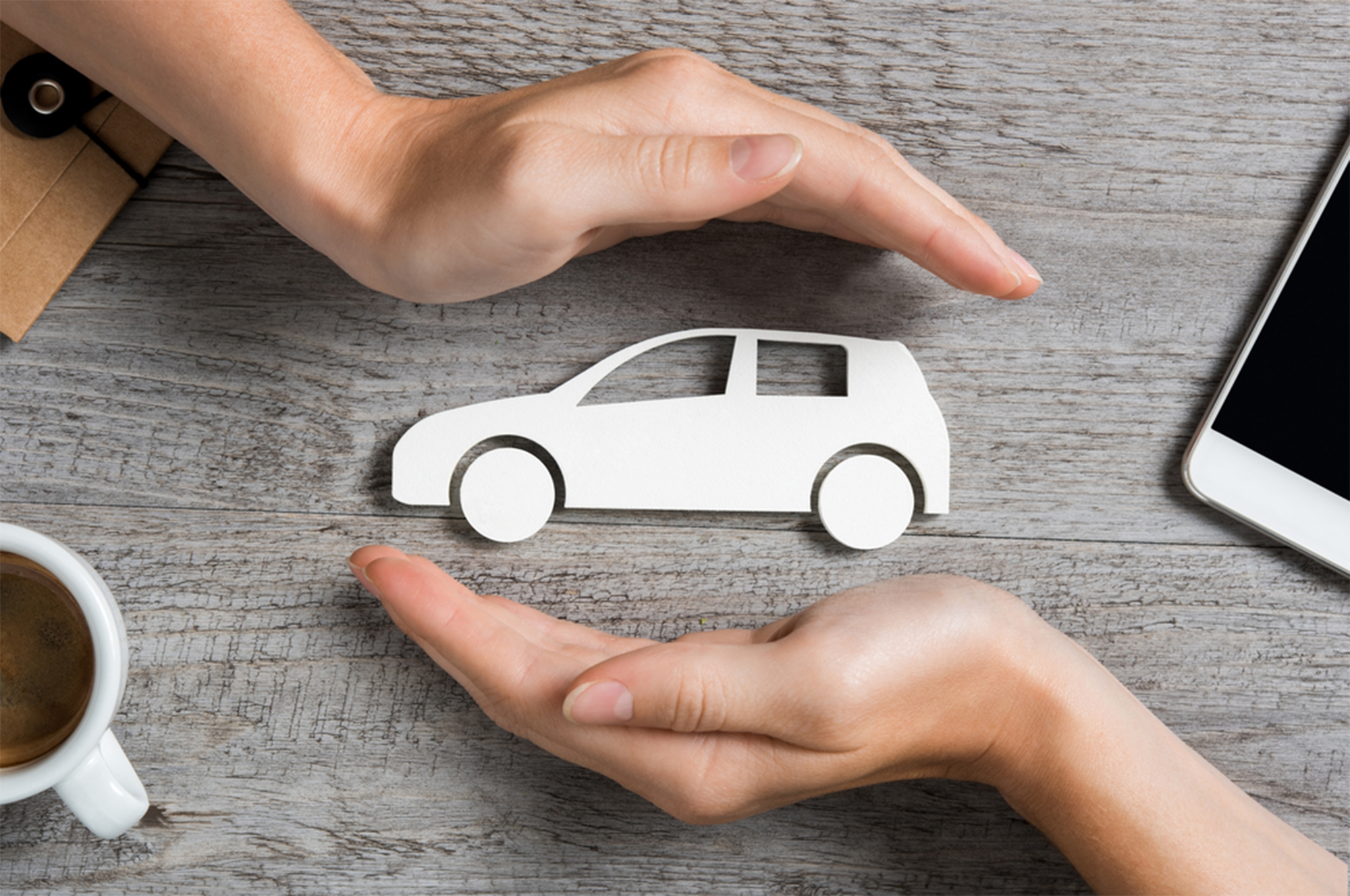 Hands,Protecting,Icon,Of,Car,Over,Wooden,Table.,Top,View